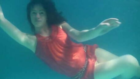 Red dressed mermaid Rusalka swimming in the pool